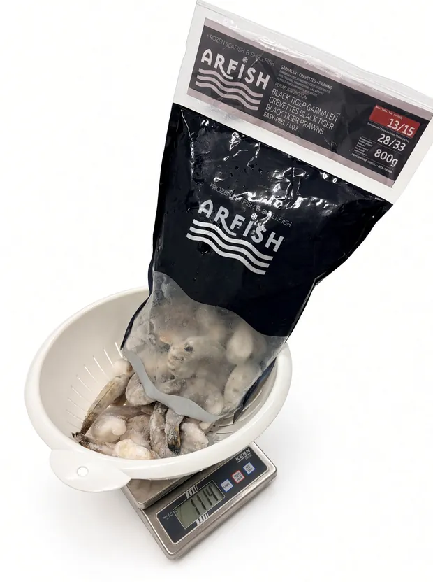 Een zak ARFISH Black Tiger wordt leeggemaakt in het vergiet op de weegschaal.